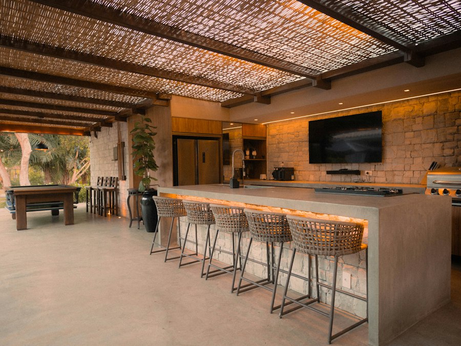 A covered outdoor kitchen with bar seating and built-in grill