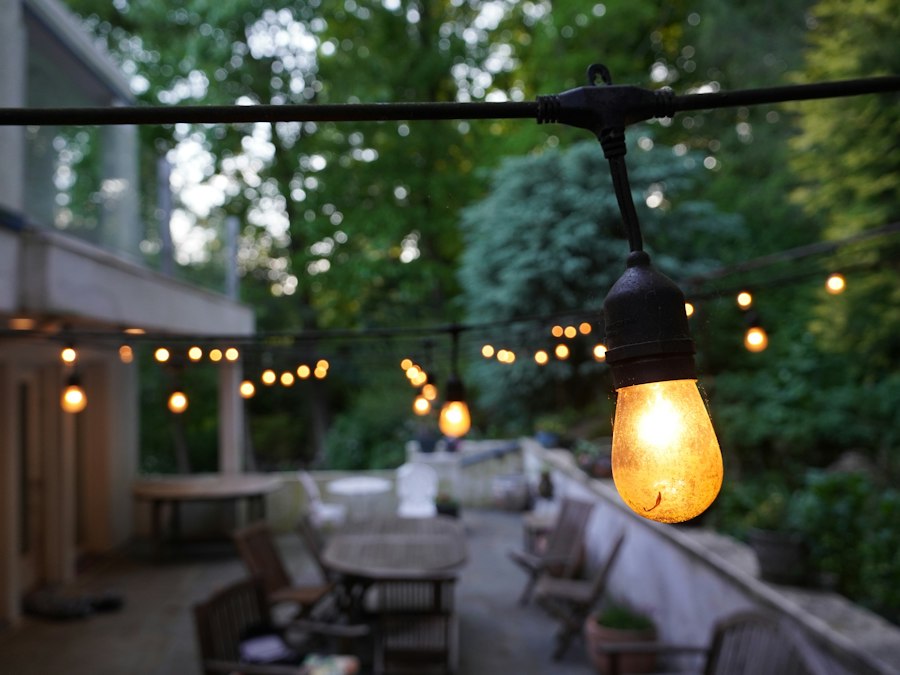 A patio dining area lit by overhead string lights at dusk
